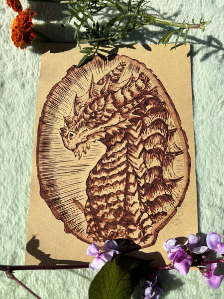 woodburning print of dragon on kraft paper